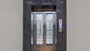 Un ascensor con acabados metálicos, paneles de vidrio y una pantalla digital.