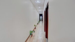 A corridor with white walls, a wooden floor, and potted plants. - Super Collection O Chet Singh Ghat (Varanasi)