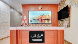 Un mostrador de recepción con un reloj, un televisor y un letrero que indica que el servicio es de la empresa.