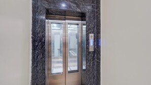 An elevator with a metallic finish and a marble-like wall surrounding it. - Super Collection O Chet Singh Ghat (Varanasi)