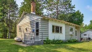 Une maison de plain-pied avec une cheminée, un porche à l’avant et un petit garage attenant.