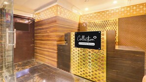 Uma área de recepção com uma placa 'Collection', um balcão de madeira e uma parede estampada.