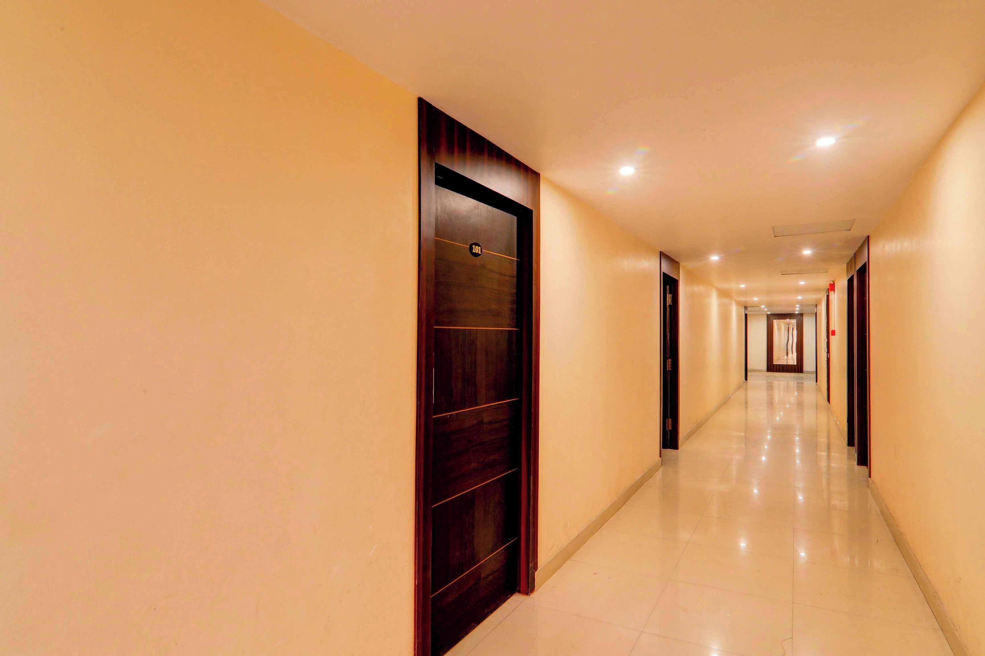A long, well-lit corridor with doors on one side and a tiled floor.