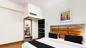 Quarto de hotel com uma cama grande, um guarda-roupa, um espelho e um quadro na parede.