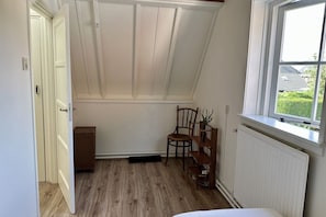 A room with a sloped ceiling, a window with a view of greenery, a radiator, and a chair. - Lovely holiday home centrally located in Bergen in delightful surroundings. (Bergen)