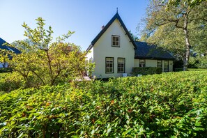 A white house with a steep gabled roof, surrounded by dense greenery and trees. - Lovely holiday home centrally located in Bergen in delightful surroundings. (Bergen)