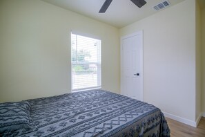 A bedroom with a bed, a window with blinds, a door, and a ceiling fan. - Near San Antonio River Walk w/ Fenced Yard (San Antonio)