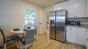 Una cocina compacta con refrigerador, microondas y comedor con sillas y mesa.