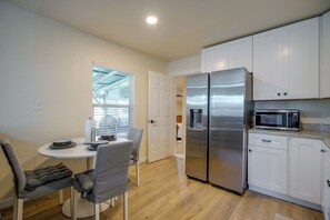 Eine kompakte Küchenzeile mit Kühlschrank, Mikrowelle und einem Essbereich mit Stühlen und Tisch.