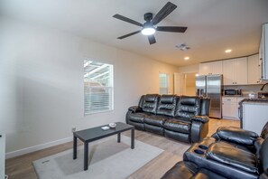 A living room with a black leather sofa, a small table, and a ceiling fan. - Near San Antonio River Walk w/ Fenced Yard (San Antonio)
