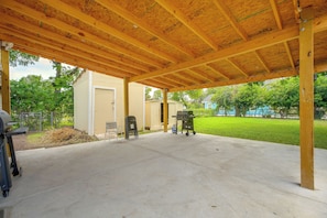 A covered patio area with a concrete floor, two barbecue grills, and a grill cart. - Near San Antonio River Walk w/ Fenced Yard (San Antonio)