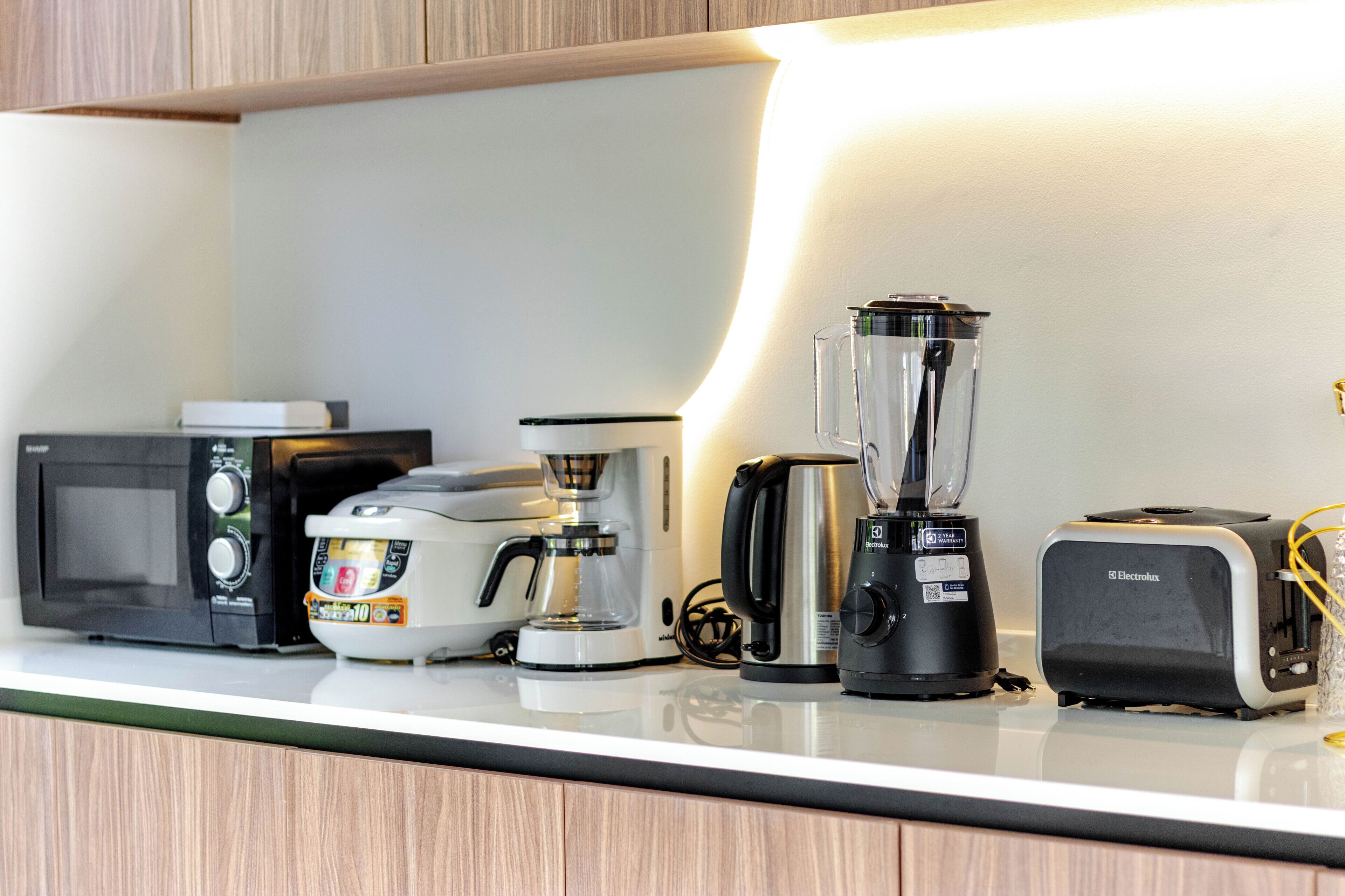Eine Küchenarbeitsfläche mit Mikrowelle, Kaffeemaschine, Mixer und Toaster.