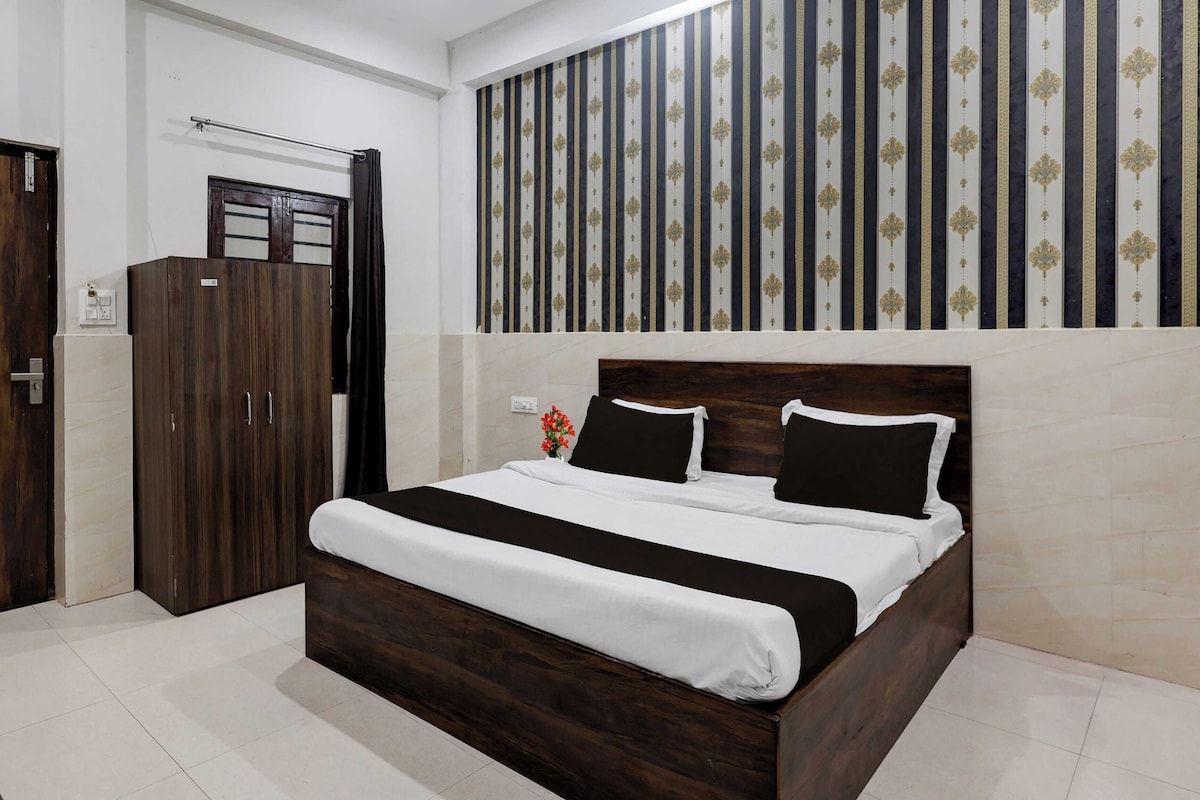 A hotel room with a wooden bed, a wardrobe, and a wall with vertical stripes.