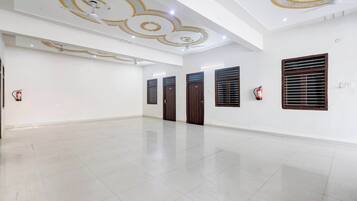A spacious, well-lit room with a polished floor, decorative ceiling, and a fire extinguisher mounted on the wall.