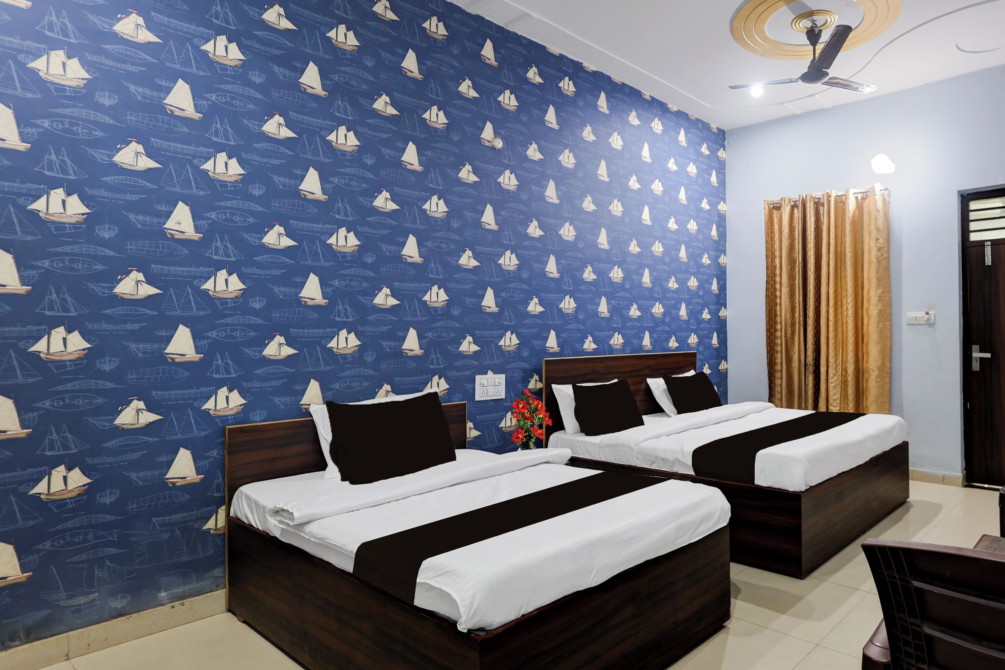 A hotel room with two beds, a ceiling fan, and a patterned wall.