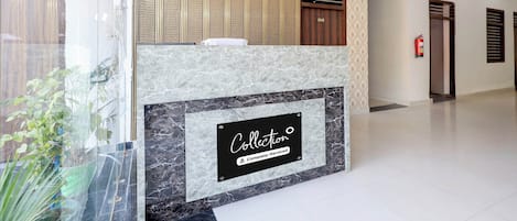 Zona de recepción de un hotel con mostrador de mármol, un cuadro enmarcado y un aire acondicionado de pared.