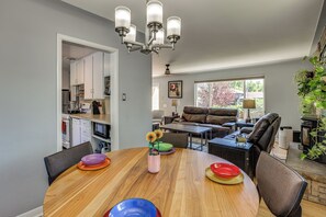 Uma cozinha moderna com armários brancos, uma mesa de jantar com pratos coloridos e um sofá de couro na sala de estar.
