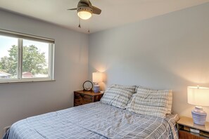 Un dormitorio con cama, mesita de noche, lámpara y ventilador de techo.