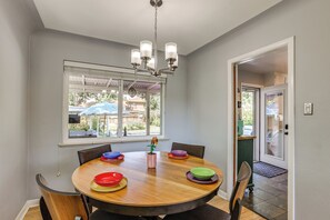 A dining area with a round table, chairs, a chandelier, and a window with a view of the outdoors. - Spacious Denver Getaway w/ Pool, Hot Tub & More (Denver)