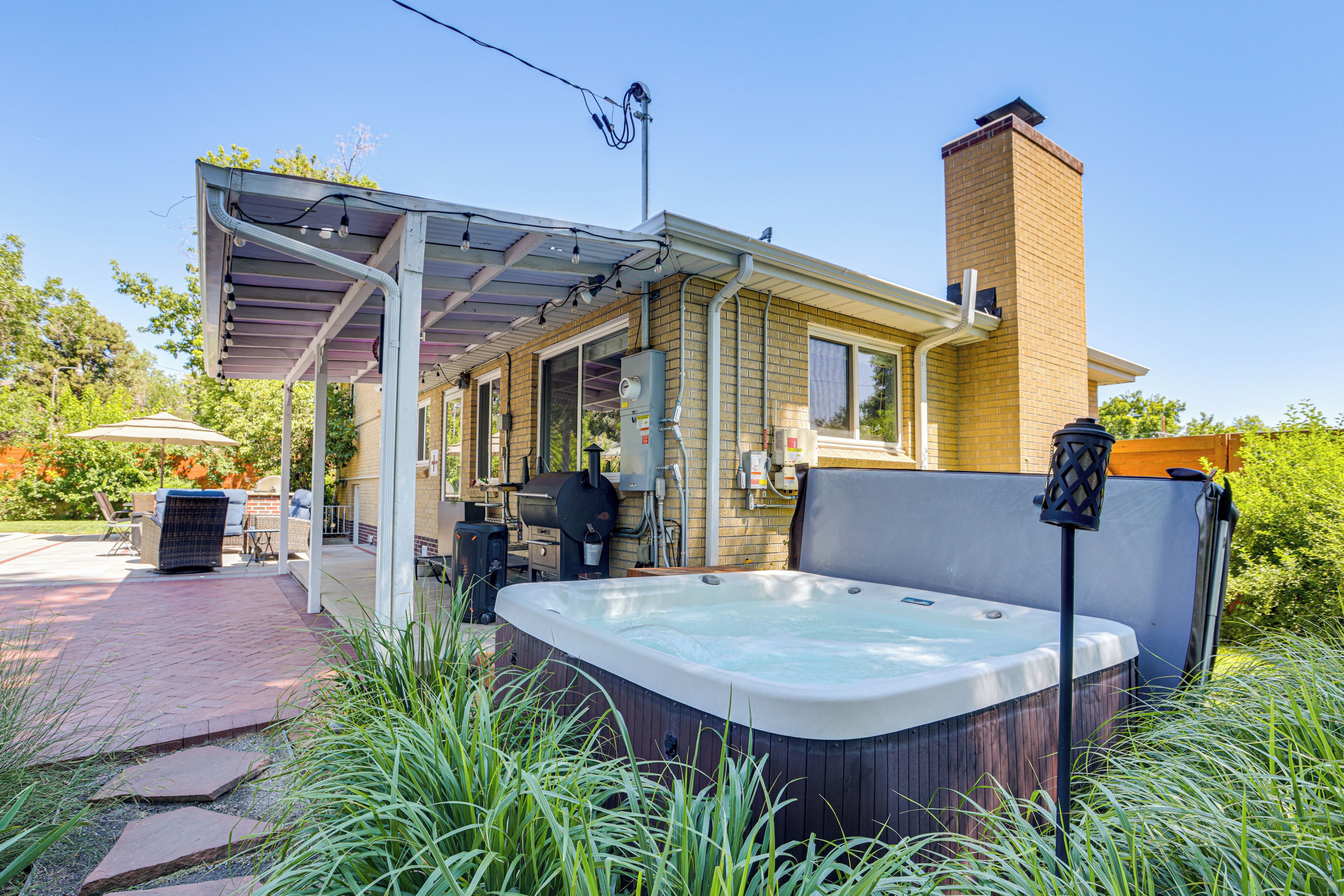 A covered patio area with a hot tub, outdoor furniture, and a barbecue grill.