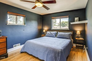 A bedroom with a bed, two bedside tables with lamps, a ceiling fan, and two windows. - Spacious Denver Getaway w/ Pool, Hot Tub & More (Denver)