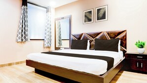 Ein modernes Hotelzimmer mit einem großen Bett, einem Nachttisch, einem Spiegel und zwei gerahmten Blätterbildern an der Wand.