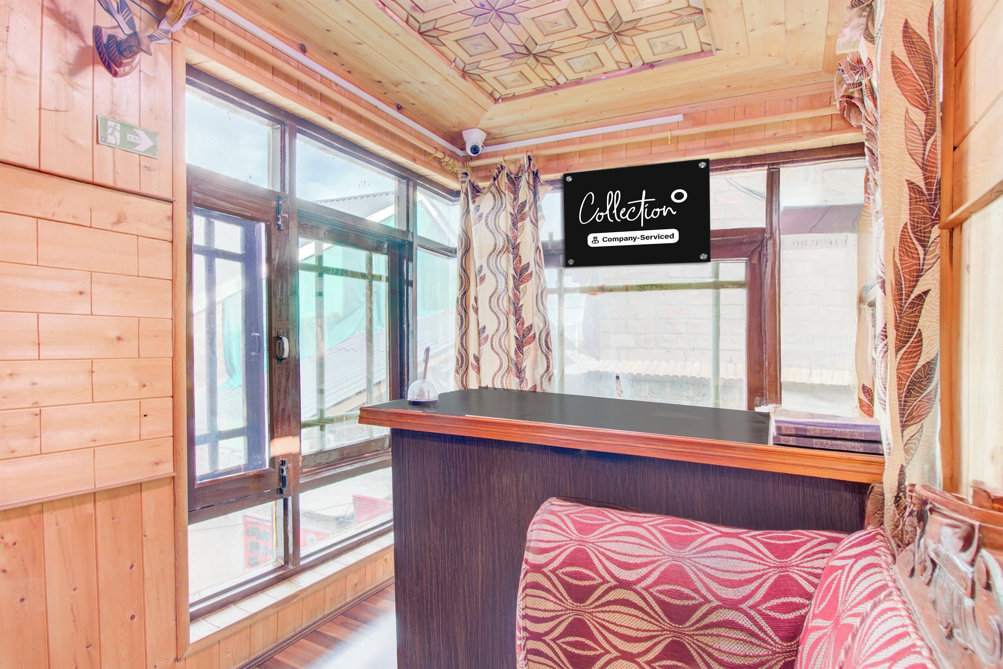 A cabin interior with a wooden ceiling, a window with a view, a bench, and a sign indicating a collection service.