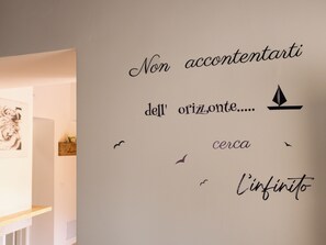 A wall with a quote in Italian, a compass symbol, and a sailboat.