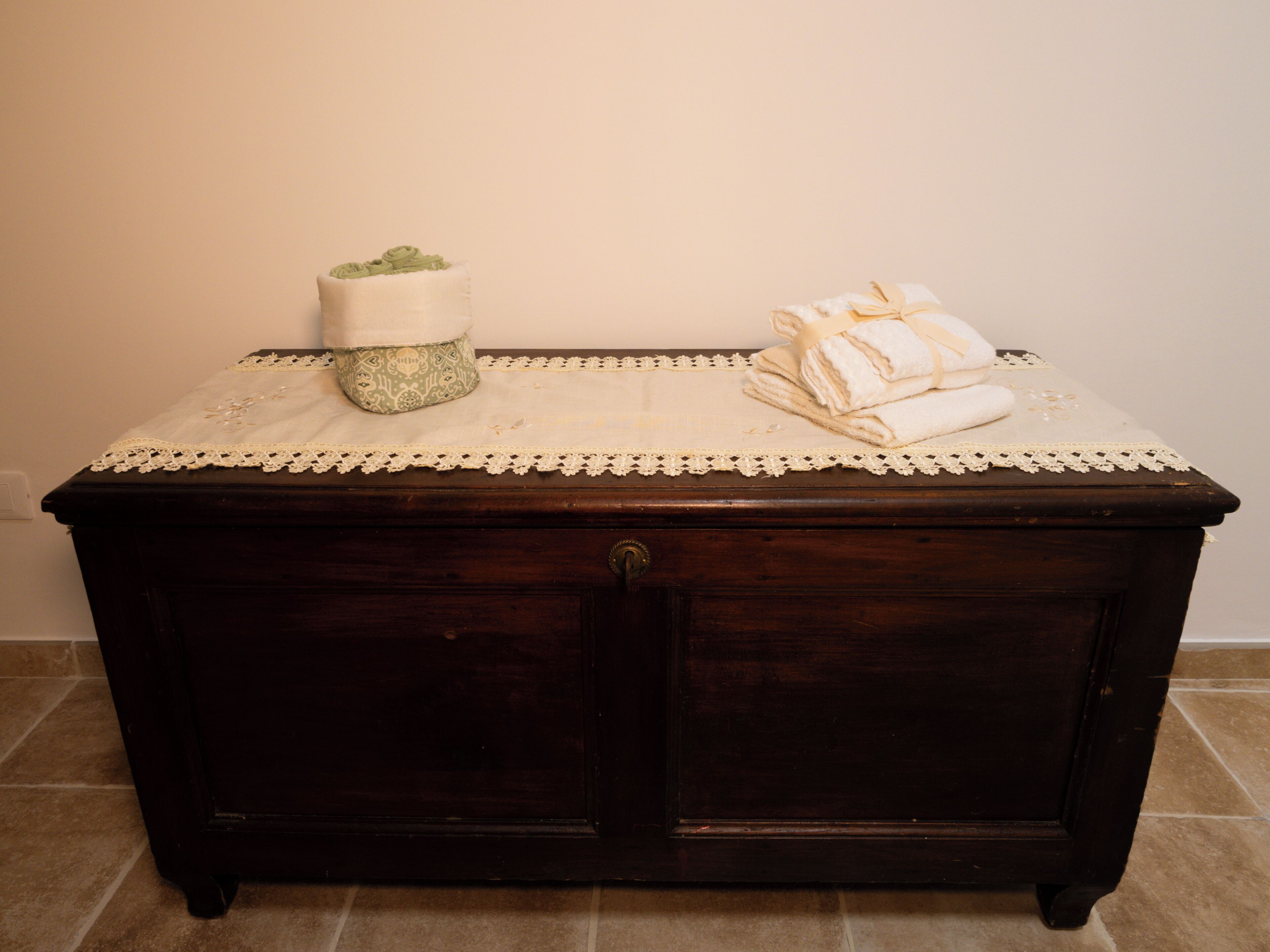 Un aparador de madera oscura con un mantel de encaje blanco y un cojín verde encima.