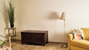 Een zithoek met een bank, een klein houten kastje, een vloerlamp en een potplant.
