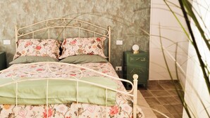 Een bed met bloemenbeddengoed, een nachtkastje in groen, en een wand met een structuur.