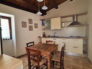 A kitchen with a wooden dining table and chairs, a stove, and a sink.
