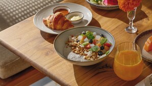 A breakfast table with a croissant, fruit, granola, and a glass of orange juice. - Emana Aruna (Penida Island)