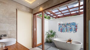 A modern bathroom with a freestanding bathtub, a wooden vanity, and a glass-enclosed shower area. - Emana Aruna (Penida Island)