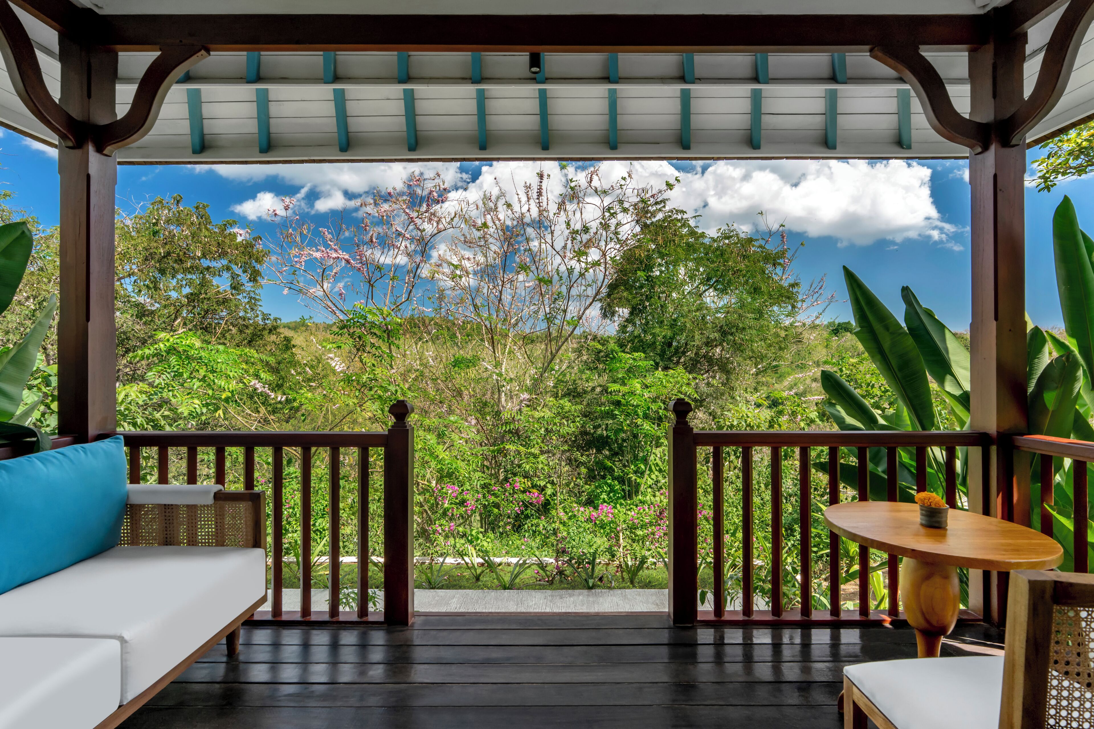 Un espacio de estar techado al aire libre con vistas a un jardín exuberante y un cielo despejado.