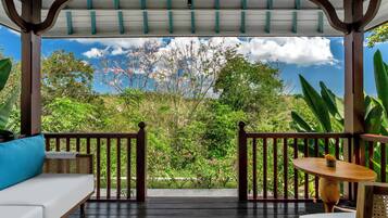 Un espacio de estar techado al aire libre con vistas a un jardín exuberante y un cielo despejado.