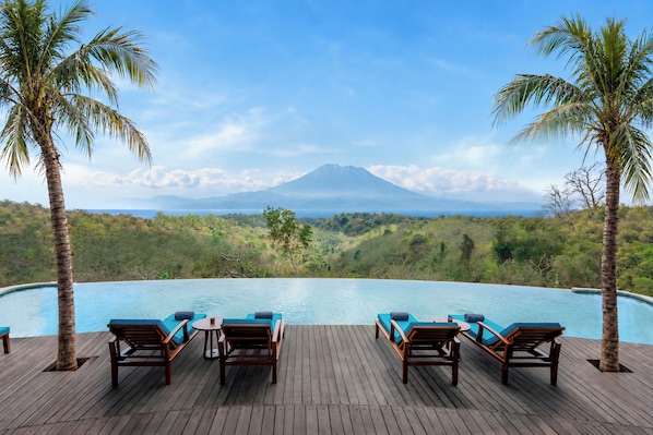 A poolside area with lounge chairs and a view of a mountain.