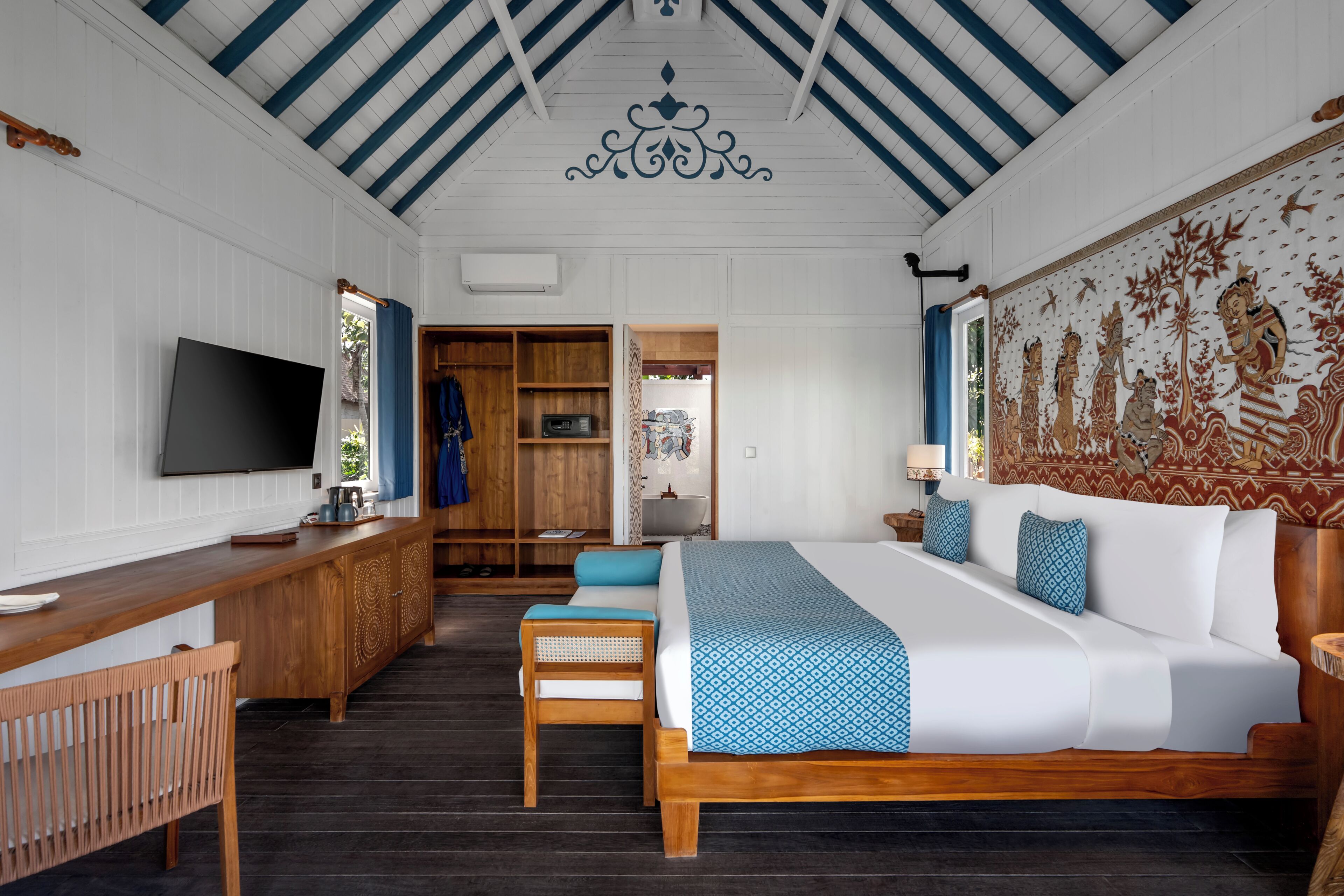 Een hotelkamer met een groot bed, een bureau, een televisie en een kledingkast.