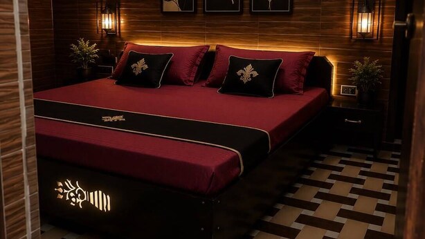 Un dormitorio moderno con una cama grande, paneles de madera oscura, una obra de arte en la pared y lámparas de noche.