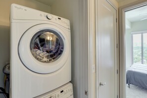 Eine frontgeladene Whirlpool Duet Waschmaschine in einem Waschraum mit einer Tür, die auf einen Balkon führt.
