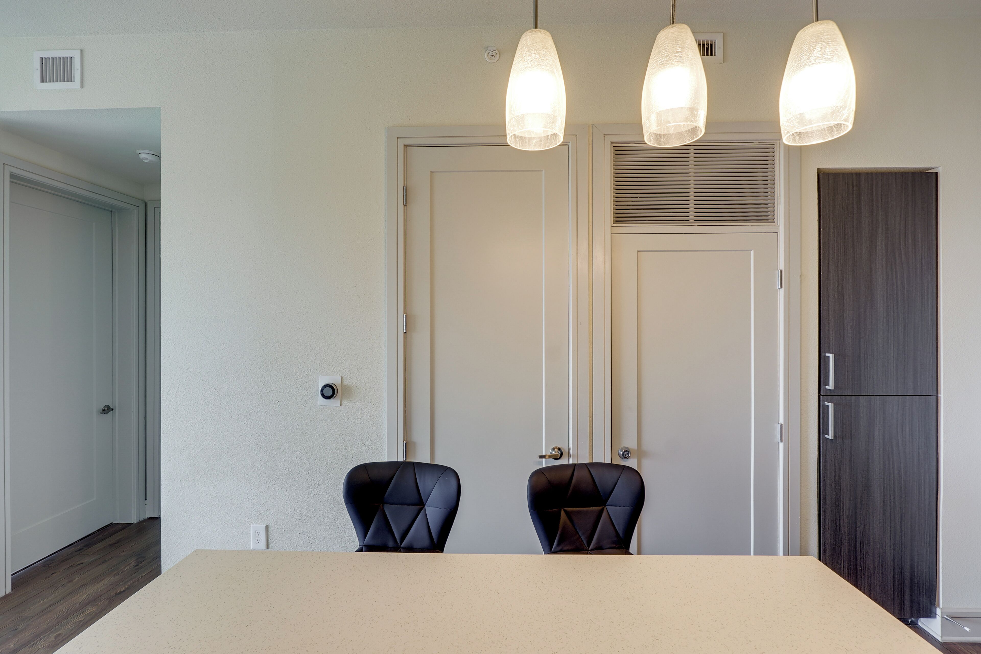 Une pièce comprenant une table à manger, deux chaises, une porte et une armoire.