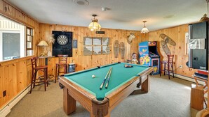 A pool table with pool cues, a dartboard, and a jukebox in a room with wooden walls and ceiling. - Lake Champlain Studio: Fish, Play & Relax (Willsboro)