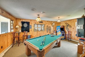 A pool table with pool cues, a dartboard, and a jukebox in a room with wooden walls and ceiling. - Lake Champlain Studio: Fish, Play & Relax (Willsboro)