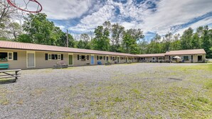 A motel with multiple rooms, a gravel parking area, and a basketball hoop. - Lake Champlain Studio: Fish, Play & Relax (Willsboro)