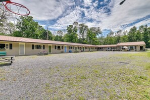 A motel with multiple rooms, a gravel parking area, and a basketball hoop. - Lake Champlain Studio: Fish, Play & Relax (Willsboro)