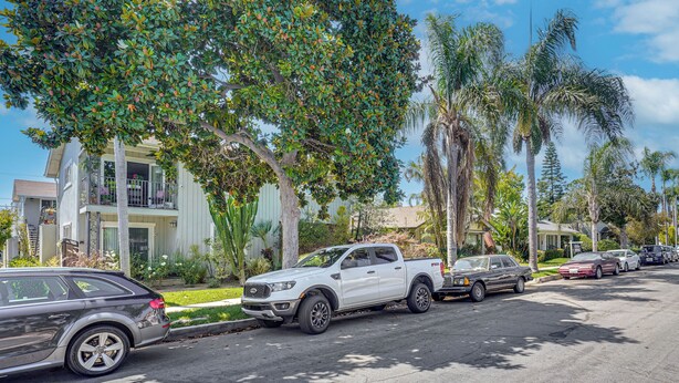 Una calle residencial con coches estacionados, árboles y casas.