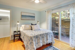 Ein Schlafzimmer mit einem Bett, Nachttischlampen, einem Gemälde und Blick ins Freie.