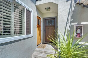 Ein Haus mit einer Holztür, einem Fenster mit Rollläden und einer kleinen Veranda mit Stufen.