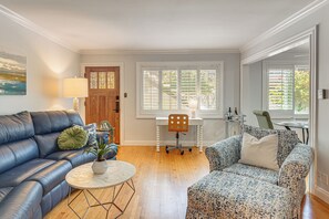 Ein Wohnzimmer mit einem blauen Sofa, einem gemusterten Sessel, einem kleinen runden Tisch und einer Holztür mit Buntglasfeldern.