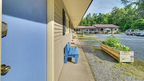 Een motel met een overdekte veranda, een blauwe bank en een plantenbak met groen.